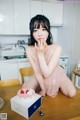 A woman sitting at a table with a cake in front of her.