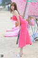 A woman in a pink dress standing on a beach.