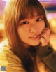 A young woman with long brown hair and bangs smiles at the camera.