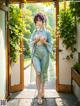 A woman in a blue kimono standing in front of a door.