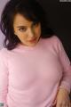 A woman in a pink sweater posing for a picture.