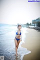 A woman in a blue bikini standing in the water.