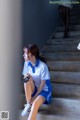 A woman sitting on the steps of a building holding a cell phone.