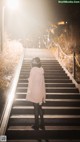 A woman in a pink coat is walking up some stairs.