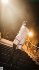 A woman in a white shirt and black stockings is standing on some stairs.