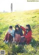 A group of young women sitting on top of a lush green field.